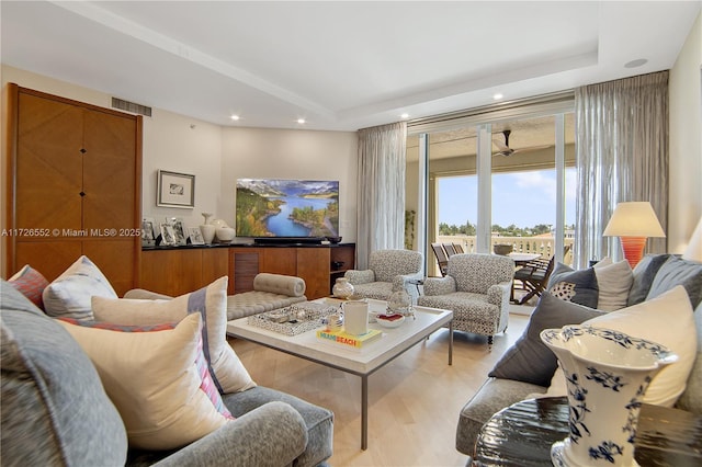 living room featuring light hardwood / wood-style floors and a raised ceiling