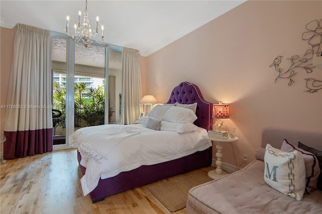 bedroom with an inviting chandelier, access to outside, and light wood-type flooring