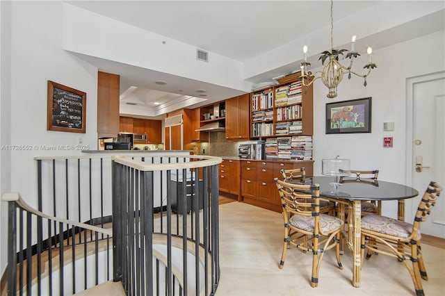 dining space featuring a raised ceiling, a notable chandelier, and light wood-type flooring