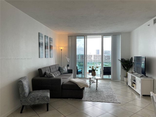 living room featuring light tile patterned floors, visible vents, and a wall of windows