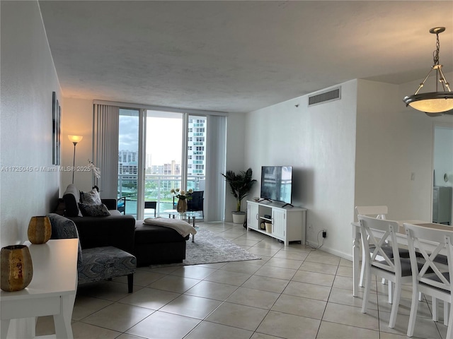 living room featuring light tile patterned floors, a wall of windows, visible vents, and baseboards