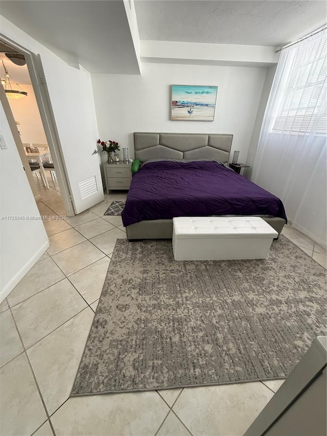 bedroom with a textured ceiling, baseboards, and light tile patterned floors