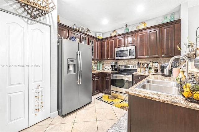 kitchen with light tile patterned flooring, appliances with stainless steel finishes, dark brown cabinetry, and sink