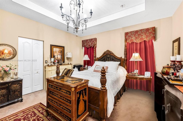 carpeted bedroom featuring a raised ceiling, a closet, and an inviting chandelier