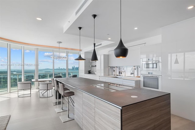 100 S Pointe Dr Unit 3203, Miami Beach, FL 33139 - kitchen featuring modern cabinets, stainless steel double oven, plenty of natural light, white cabinetry, and a wall of windows