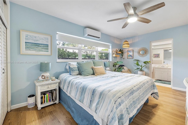 bedroom with wood-type flooring, connected bathroom, a wall mounted AC, and ceiling fan