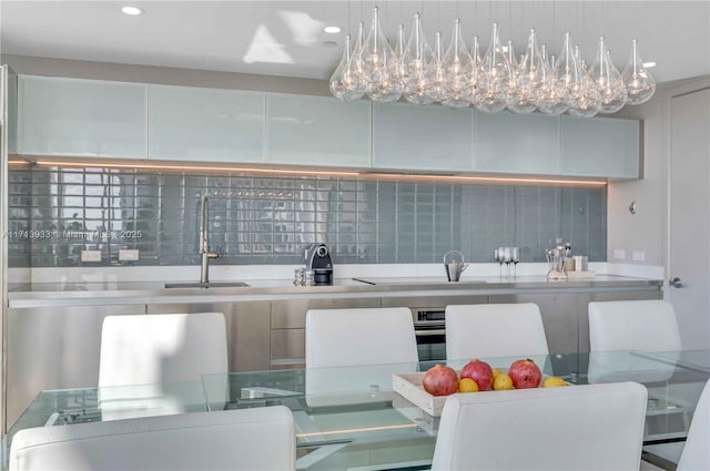 kitchen featuring decorative backsplash, sink, stovetop, and pendant lighting