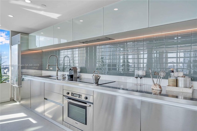 kitchen with white cabinetry, decorative backsplash, sink, oven, and black electric cooktop