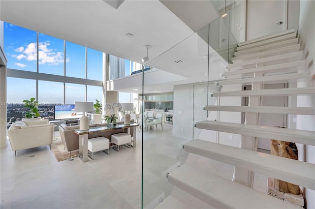 stairway featuring floor to ceiling windows, a high ceiling, and tile patterned flooring