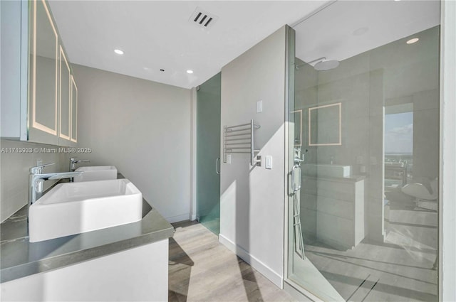 bathroom with a shower with shower door, decorative backsplash, hardwood / wood-style flooring, and vanity