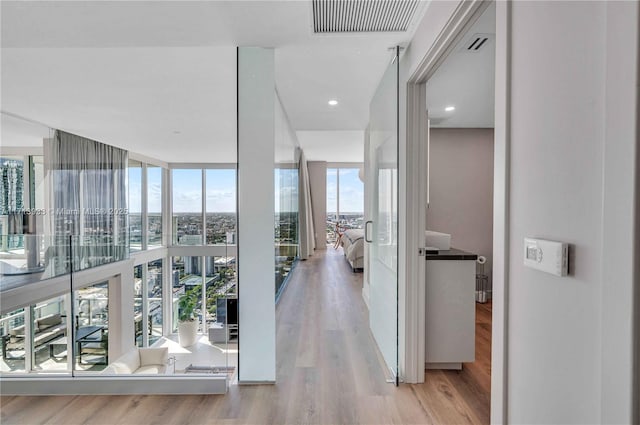 hall with expansive windows and light hardwood / wood-style flooring