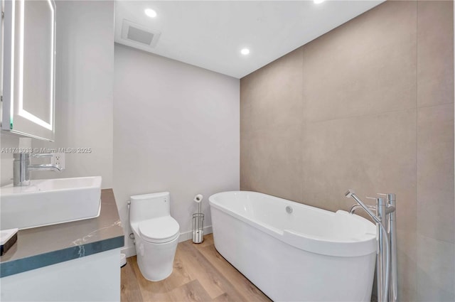 bathroom with toilet, a bathtub, wood-type flooring, and sink