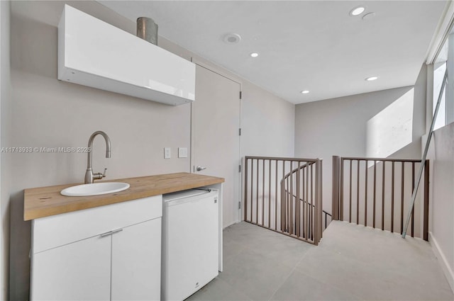 kitchen featuring white cabinets, fridge, and sink