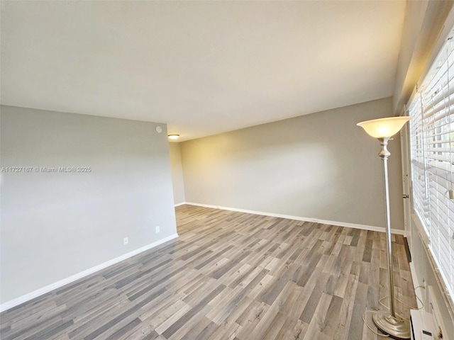 unfurnished room with baseboards and light wood-style floors