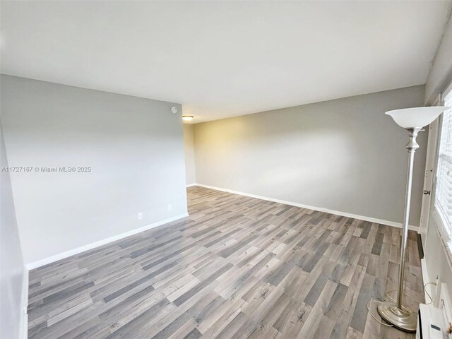 unfurnished bedroom featuring ceiling fan, access to exterior, dark hardwood / wood-style floors, a wall mounted air conditioner, and multiple closets