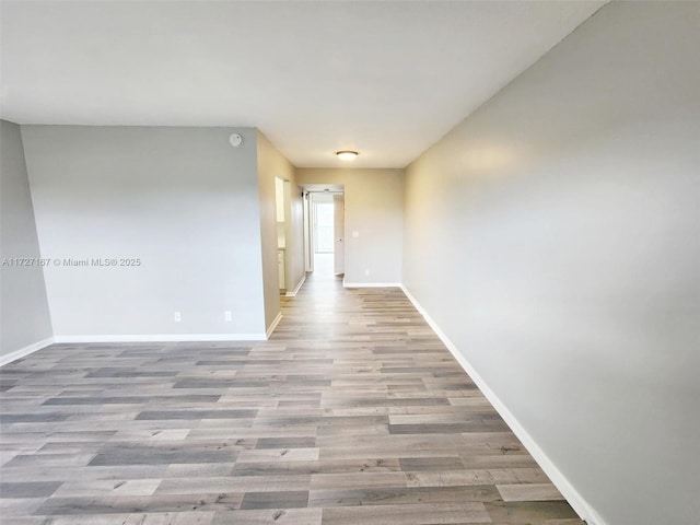 spare room featuring baseboards and wood finished floors