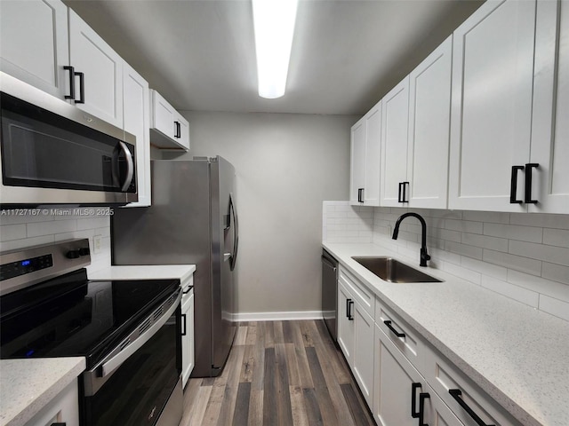 kitchen featuring white cabinets, dark wood finished floors, decorative backsplash, stainless steel appliances, and a sink