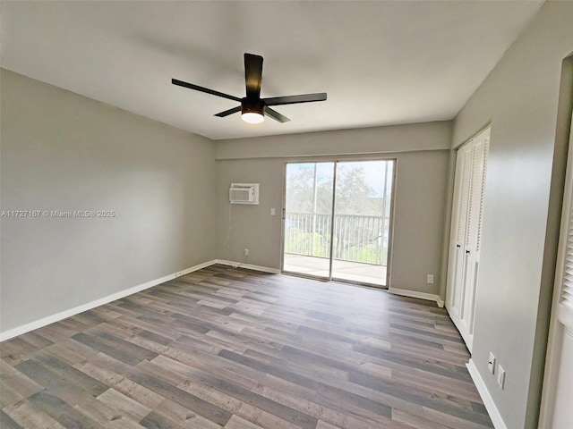 unfurnished room with a ceiling fan, baseboards, wood finished floors, and a wall mounted AC