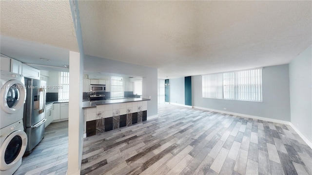 living room featuring a textured ceiling, light hardwood / wood-style flooring, and stacked washing maching and dryer