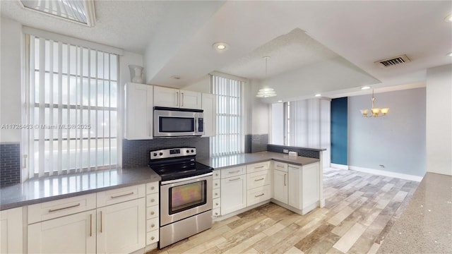 kitchen featuring decorative light fixtures, appliances with stainless steel finishes, tasteful backsplash, and white cabinetry