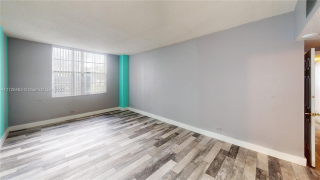 empty room featuring a textured ceiling and light hardwood / wood-style flooring