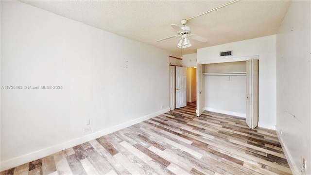 unfurnished bedroom with ceiling fan, a closet, light wood-type flooring, and a textured ceiling