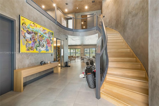 stairway with a towering ceiling and tile patterned flooring