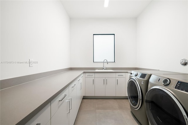 laundry area with sink, light tile patterned floors, washing machine and dryer, and cabinets