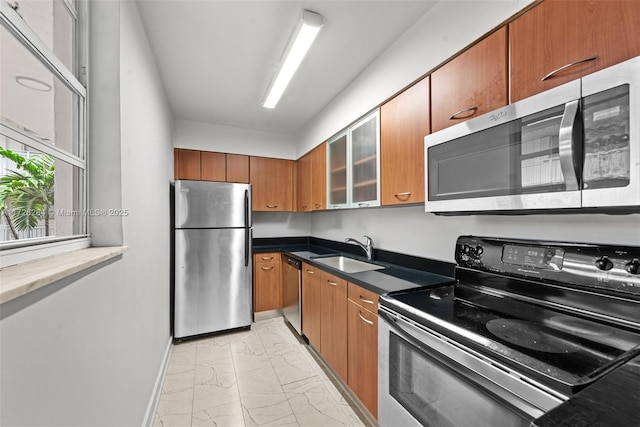 kitchen featuring glass insert cabinets, appliances with stainless steel finishes, brown cabinetry, marble finish floor, and a sink