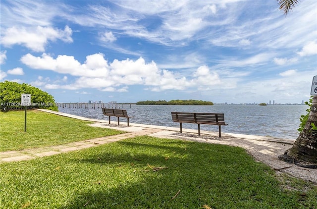 view of dock with a water view and a lawn