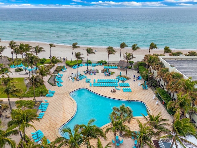 view of pool with a water view, a patio area, and a view of the beach