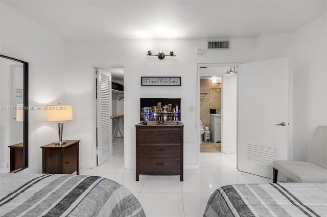 tiled bedroom featuring ensuite bathroom and a closet