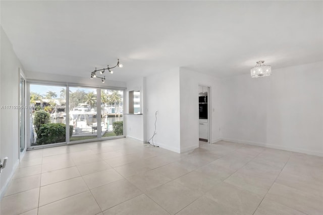 spare room featuring track lighting, baseboards, and light tile patterned floors