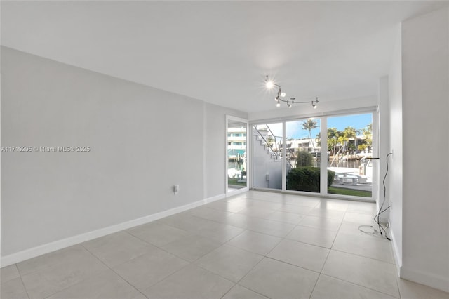 unfurnished room with track lighting, baseboards, and light tile patterned floors