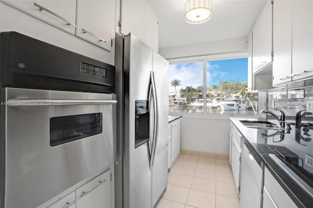 kitchen with appliances with stainless steel finishes, white cabinetry, a sink, and light tile patterned flooring