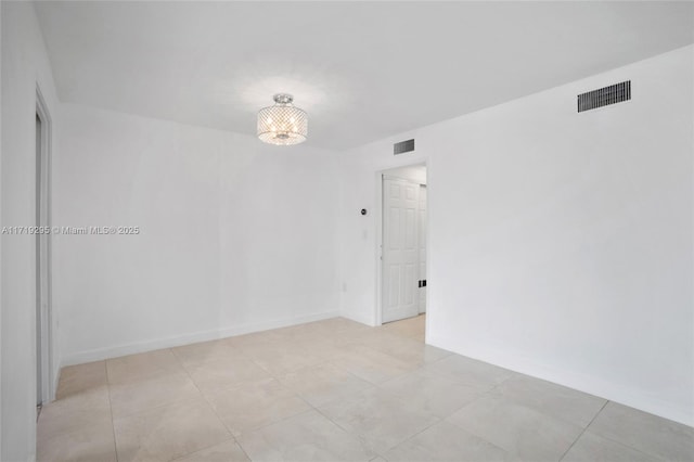 unfurnished room with baseboards and visible vents