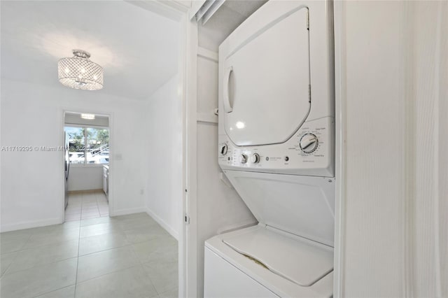 laundry area with stacked washer and clothes dryer, light tile patterned flooring, and baseboards