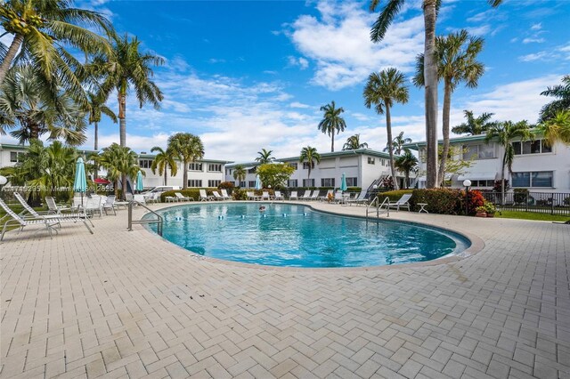 community pool with a patio area and fence