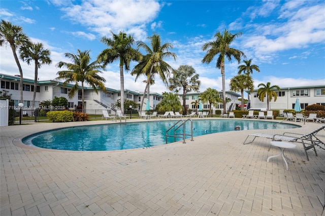 community pool with a residential view, a patio area, and fence