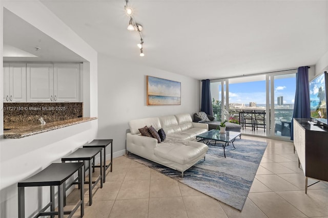 living room with a wall of windows and light tile patterned floors