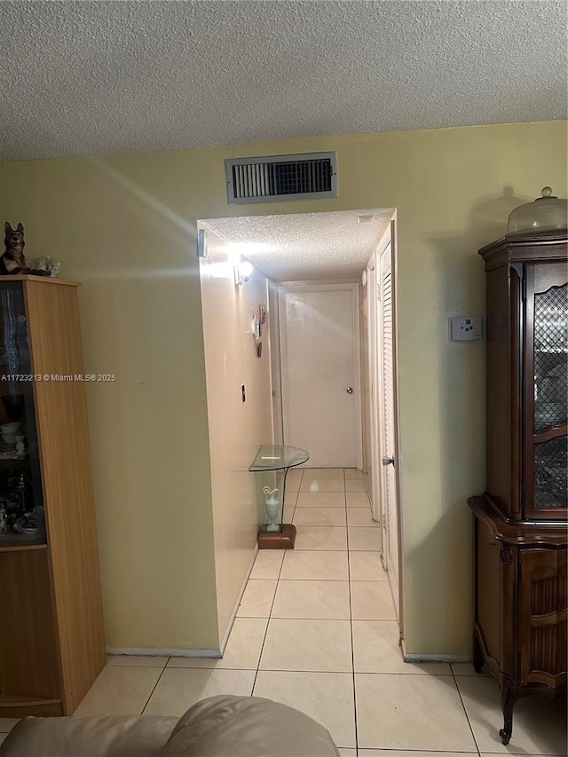 hallway with light tile patterned floors and a textured ceiling