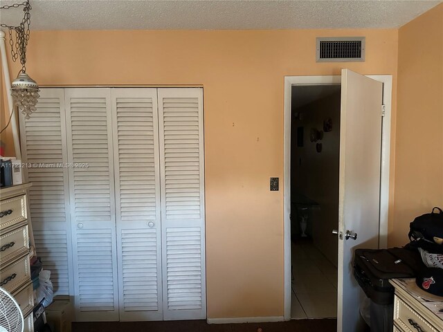 bedroom with tile patterned flooring, a closet, and a textured ceiling