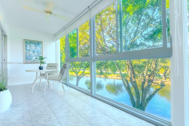 unfurnished sunroom with ceiling fan and a water view