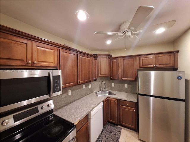 kitchen featuring a sink, backsplash, appliances with stainless steel finishes, light tile patterned flooring, and ceiling fan