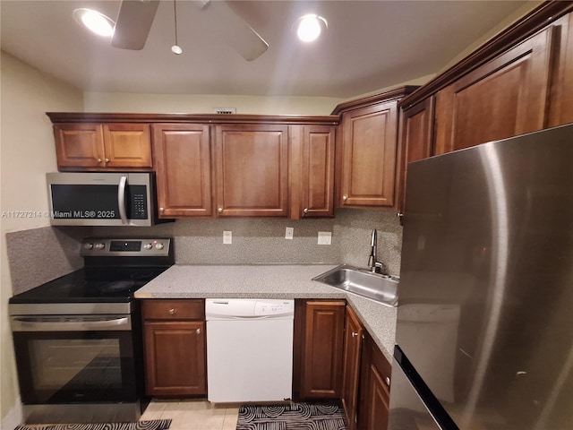 kitchen featuring light tile patterned floors, tasteful backsplash, appliances with stainless steel finishes, a ceiling fan, and a sink