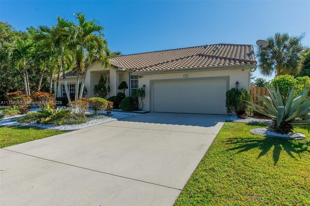 mediterranean / spanish home with a garage and a front lawn