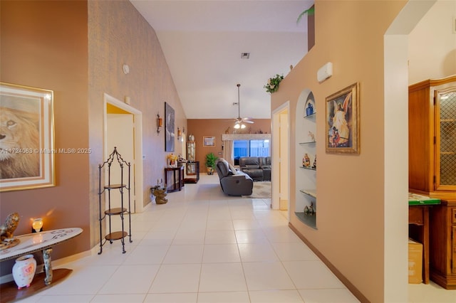 corridor with high vaulted ceiling, light tile patterned floors, and built in features