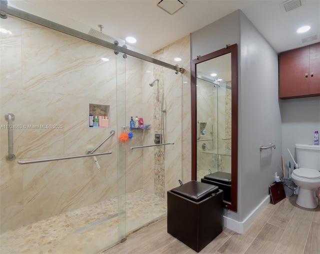 bathroom featuring a shower with shower door and toilet