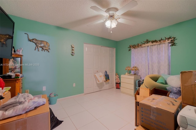 bedroom featuring a textured ceiling, ceiling fan, light tile patterned flooring, and a closet