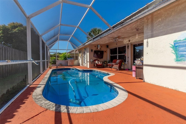 view of swimming pool with ceiling fan, glass enclosure, and a patio